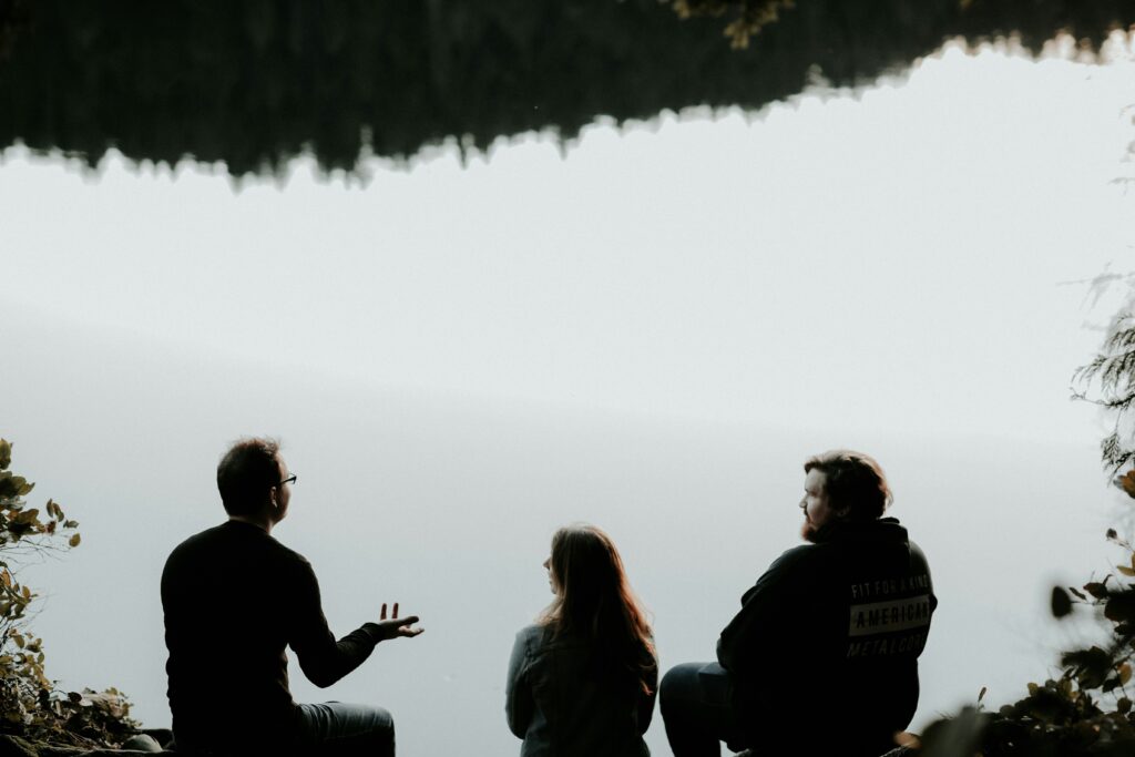 霧の降るなか、崖の上に座る3人の写真