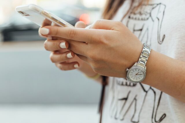 街中でスマホを見ている女性の手